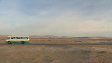 Bus fährt durch karge Wüstenlandschaft
