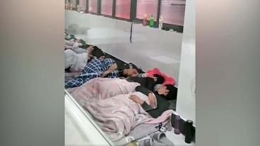 Arbeiter schlafen dicht an dicht auf Boden von Fabrik