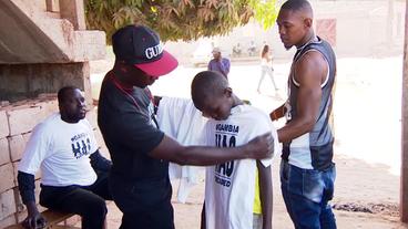 Ein Mann verteilt T-Shirts mit dem Aufdruck "Gambia has decided".