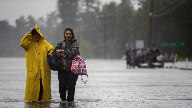 Rita Prosperie (l) und Connie McNeer gehen am 30.08.2017 in Lumberton (USA) über den vom Tropensturm Harvey überfluteten Highway 96. 