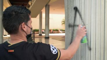 Mann sprüht Protestslogan an Wand