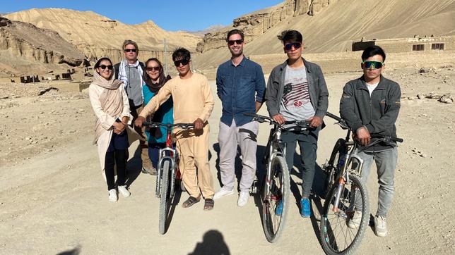 Eine Gruppe von Leuten mit Sonnenbrillen und Fahrrädern in einer wüstenähnlichen Gegend.