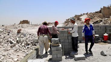 Arbeiter bauen ein Gebäude in der zerstörten Stadt Mossul wieder auf