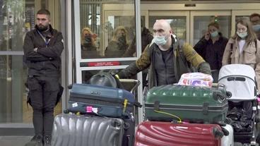 Passagiere mit Koffern kommen an Flughafen an