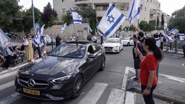 Menschen am Straßenrand mit israelischen Fahnen 