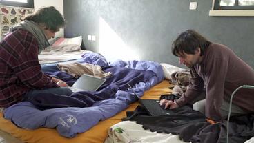Mann und Frau sitzen mit Laptops auf einem Bett
