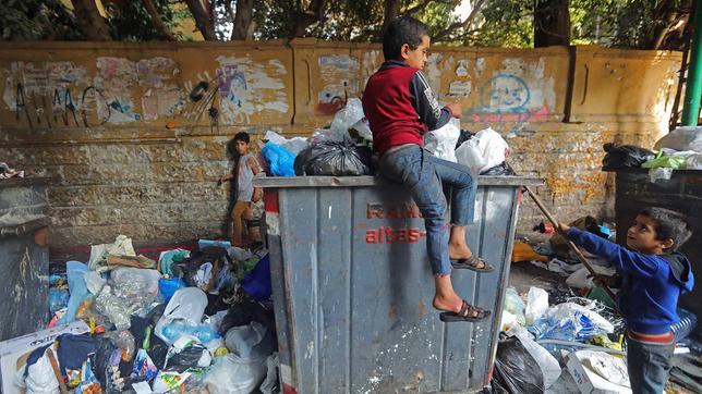 Ein Kind sucht in Abfalleimer nach brauchbaren Dingen