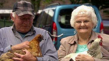 Mann und Frau mit Hühnern im Arm