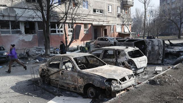 Mariupol: Menschen vor zerstörten Autos und Trümmern.