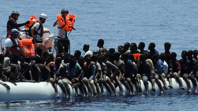 Migranten sitzen in einem überfüllten Schlauchboot auf dem Mittelmeer.