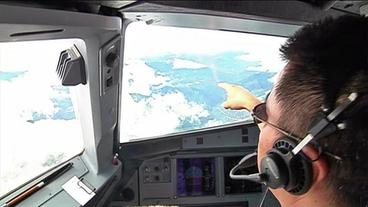 Ein Pilot zeigt aus dem Cockpit auf Bhutan.