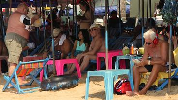 Männliche Touristen am thailändischen Strand.
