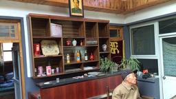 Ein Träger sitzt in einer Herberge mit Mao-Bild an der Wand.