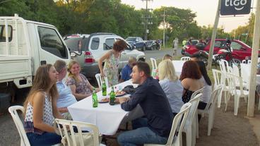 Menschen sitzen an Tischen im Freien 