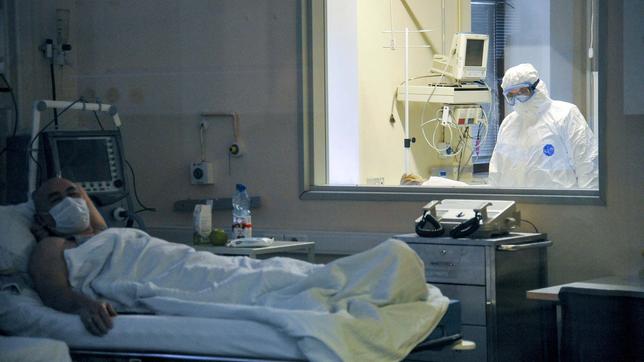 Arzt beobachtet durch ein Glasfenster einen Patienten im Krankenhaus