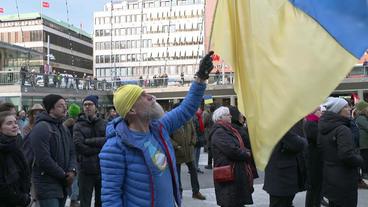 Menschen demonstrieren mit ukrainischen Fahnen gegen den Krieg 