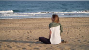 Frau sitzt am Strand