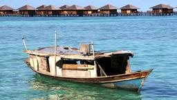 Luxus trifft Armut: Ein Bajau-Familienboot vor einem Nobelresort auf der Insel Mabul.