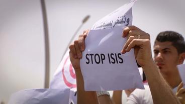 Ein Demonstrant hält ein Schild mit der Aufschrift "Stop ISIS" hoch.