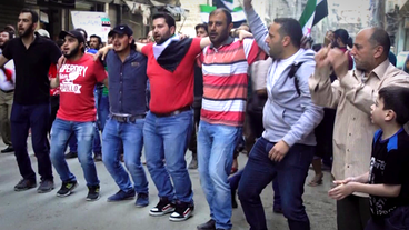 Männer tanzen in einer Reihe bei einer Demonstration in Aleppo