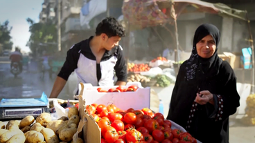 Eine Frau kauft Gemüse an einem Marktstand in Aleppo