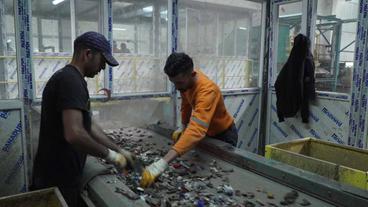 Arbeiter sortieren Plastikmüll auf Fließband