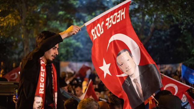 Mann schwenkt türkische Fahne mit Abbildung von Präsident Erdogan