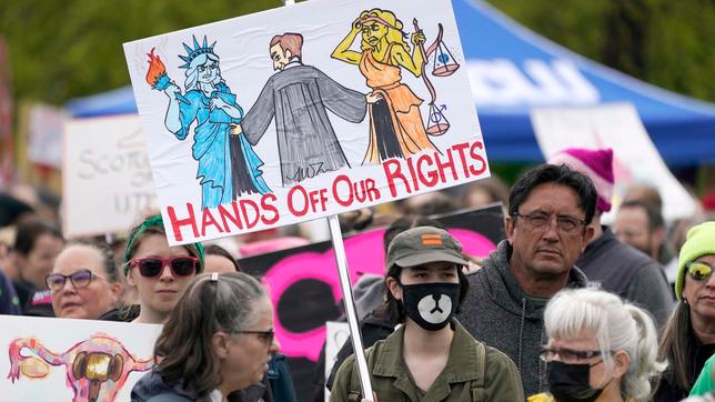 Eine Person hält ein Schild mit der Aufschrift "Hände weg von unseren Rechten" während eines Protests und einer Kundgebung für Abtreibungsrechte