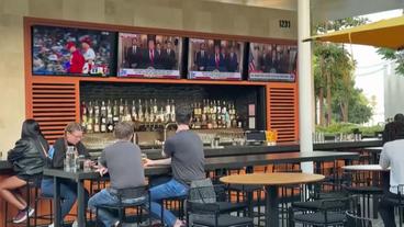 Menschen schauen auf Fernseher in einern Bar 