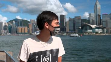Ein junger Mann schaut auf die Skyline von Hongkong.