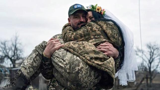 Ein Soldat trägt seine Braut auf dem Arm