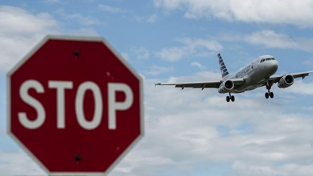 Flugzeug am Himmel, im Vordergrund ein Stop-Schild.