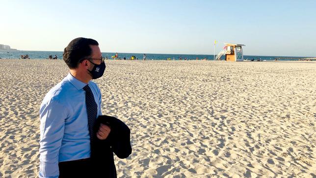 Ein Mann steht in Dubai am Strand und blickt aufs Meer.