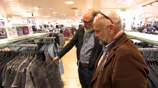 Zwei Männer begutachten Kleidung im Kaufhaus