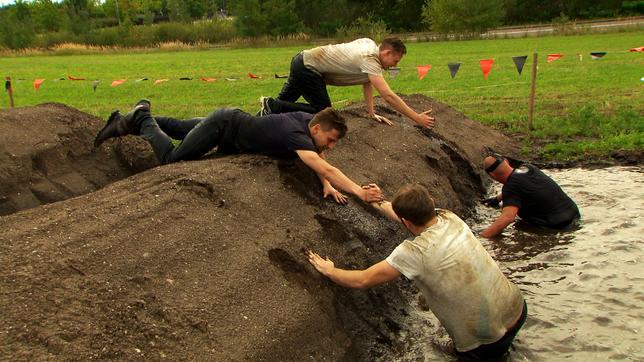 Vier Männer testen im Schlamm C&A-Kleidung