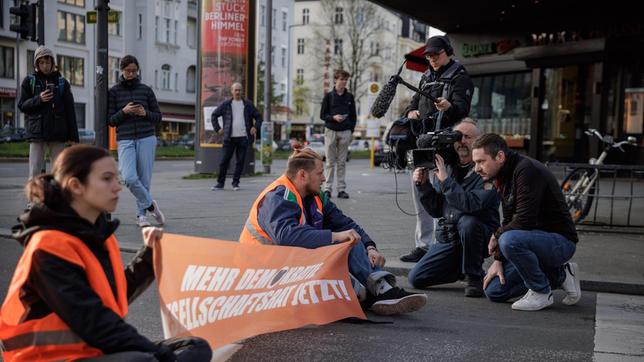 Aktivisten der "letzten Generation" werden bei einer Straßenblockade auf dem Kurfürstendamm in Berlin interviewt.