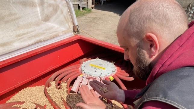 Landwirt Jonas bestückt die Sämaschine mit Kichererbsen-Saatgut.