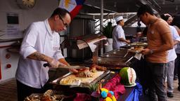 Philippinisches Buffet. Küchenchef Christian Jüngling bietet extra philippinische Spezialitäten an. Er schneidet das Fleisch.