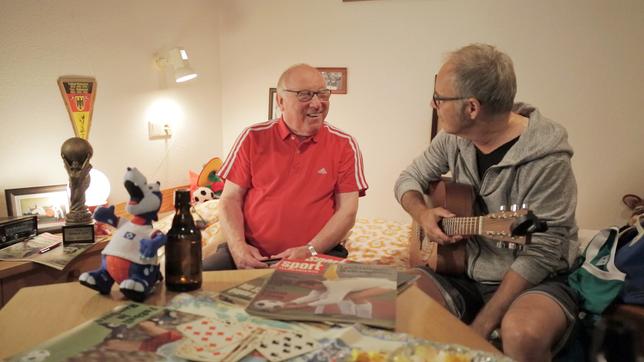 Uwe Seeler und Reinhold Beckmann sitzen in einem Zimmer in der Sportschule Malente