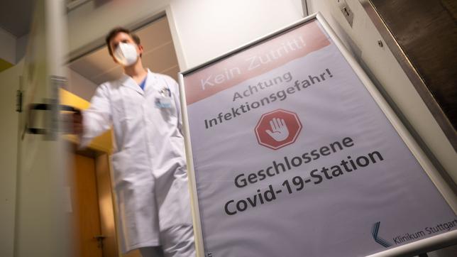 Ein Klinikmitarbeiter tritt mit Maske aus einem Corona-Isolationsbereich