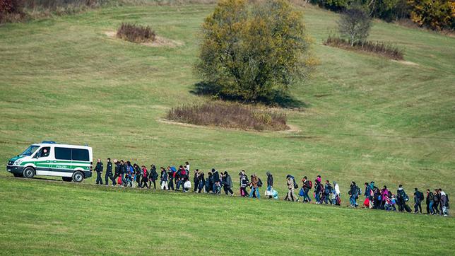 Bild: dpa Ein Zug Geflüchteter wird von der Polizei begleitet