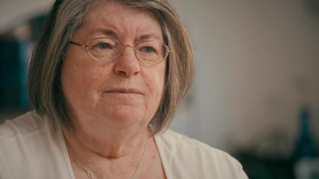Eine Frau mit grauen halblangen Haaren und Brille.