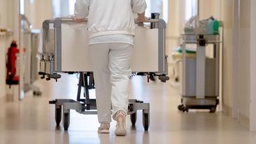 Bild: picture alliance/dpa/Marijan Murat Eine Krankenpflegerin schiebt ein Krankenbett durch einen Flur