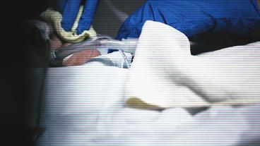 Ein Pfleger säubert den Mund eines Intensivpatienten.