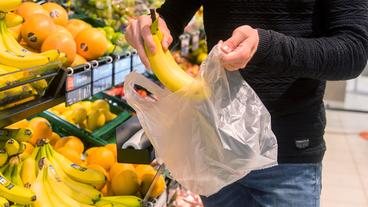 Bild: picture alliance/dpa Ein Mensch steckt eine Banane in eine Plastiktüte für Obst und Gemüse.