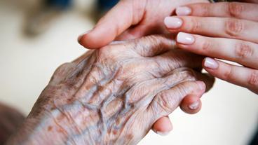 Die Hand einer alten Frau liegt in der einer jungen