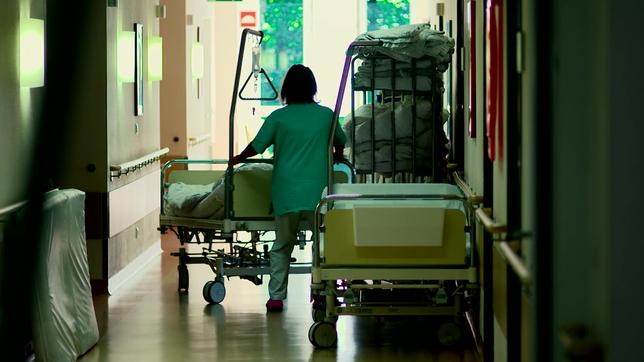 Eine Pflegekraft schiebt ein Bett auf einem Krankenhausflur
