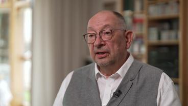 Bild: NDR Ein älterer Mann in weißem Hemd und grauer Weste und mit Brille sitzt vor einem Bücherregal. Es ist der Historiker Jan Rydel.