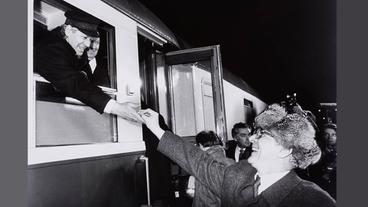Bild: J.H. Darchinger / Friedrich-Ebert-Stiftung Schwarz-Weiß-Foto: Ein Mann, der westdeutsche Politiker Helmut Schmidt, streckt seine Hand aus einem Zugfenster und berührt die Hand eines Mannes, der ostdeutsche Politiker Erich Honecker, vor dem Zug.