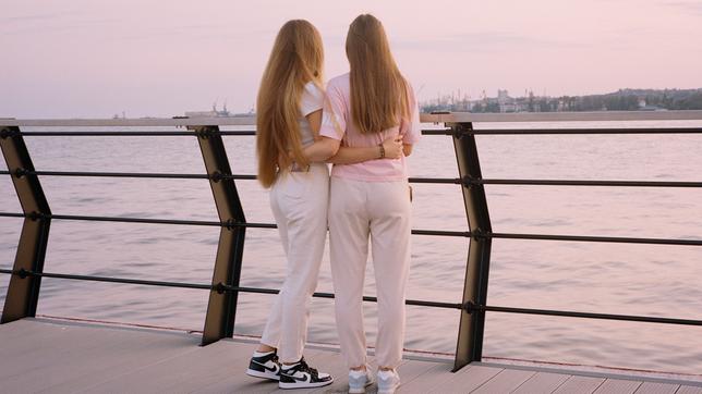 Rückansicht zweier langhaariger Mädchen an Reling stehend